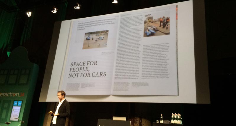 A photo of a person giving a lecture and showing a book on a projector screen. The book has the text: Space for people not for cars.