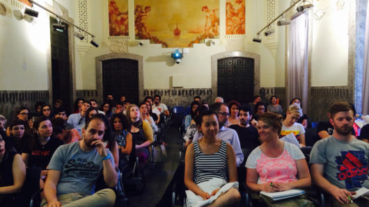 A photo of a group of students sitting in a conference hall and following a lecture.