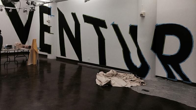 A photo of the word VENTURE painted in black on a white wall.