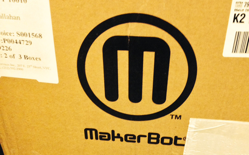 A photo showing a cardboard box with text M MakerBot that held the 3D printer.