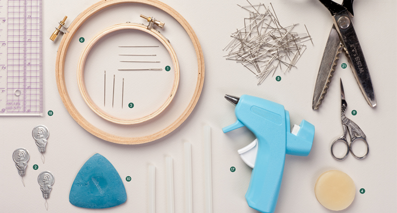 A photo showing different tools like: scissors, glue guns, clamps, pins, rulers and other.