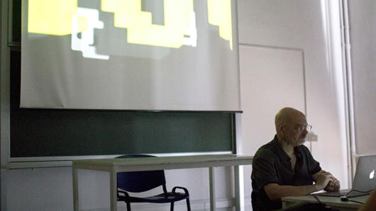 a man is presenting a course with an image projected on the wall behind him