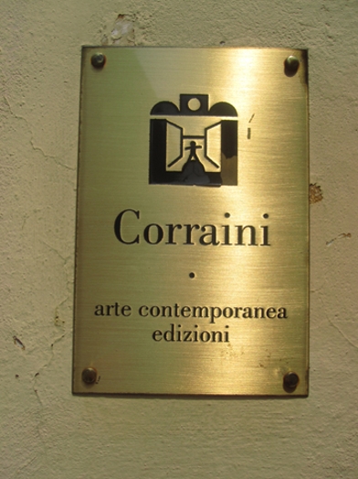 A photo of a golden plate with a logo and a text that says: Corraini arte contemporanea edizioni.
