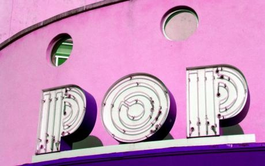 A photo of a pink building with the text POP that has neon lights tubes.