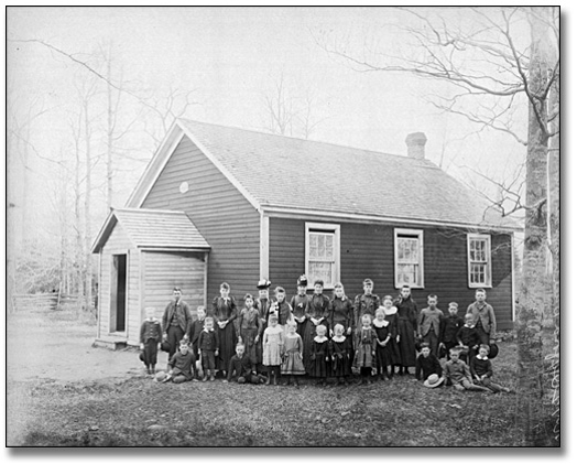 A black and white photo of a group of children in front of a house.