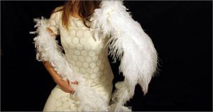 A photo of a woman's white dress with some feathers around her.