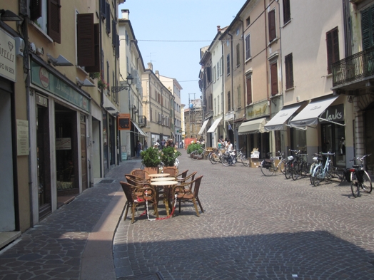 A photo of a paved narrow street with buildings close to each other.