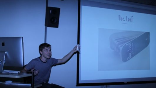 A photo of a student showing something on a screen projector.