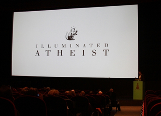 A photo of a screen projection showing a monkey drawing ant the text: Illuminated Atheist.