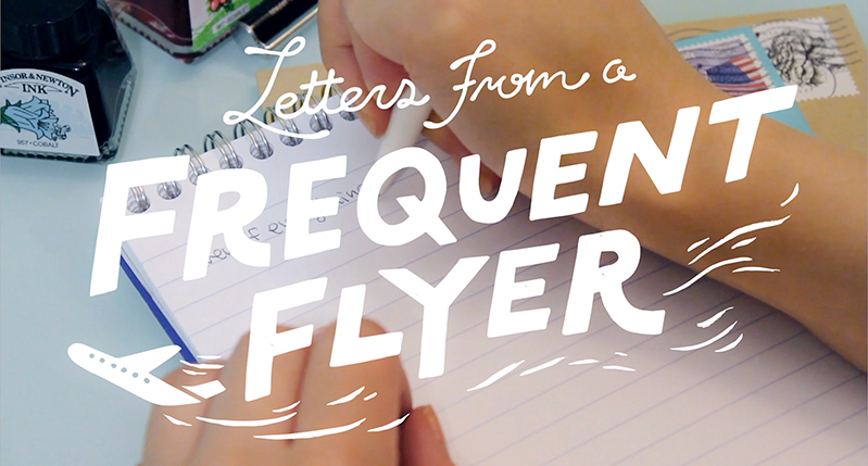 A photo of two hands holding a pencil and writing on notebook. On it there is plane pictogram and a text that reads: Letters From A Frequent Flyer.