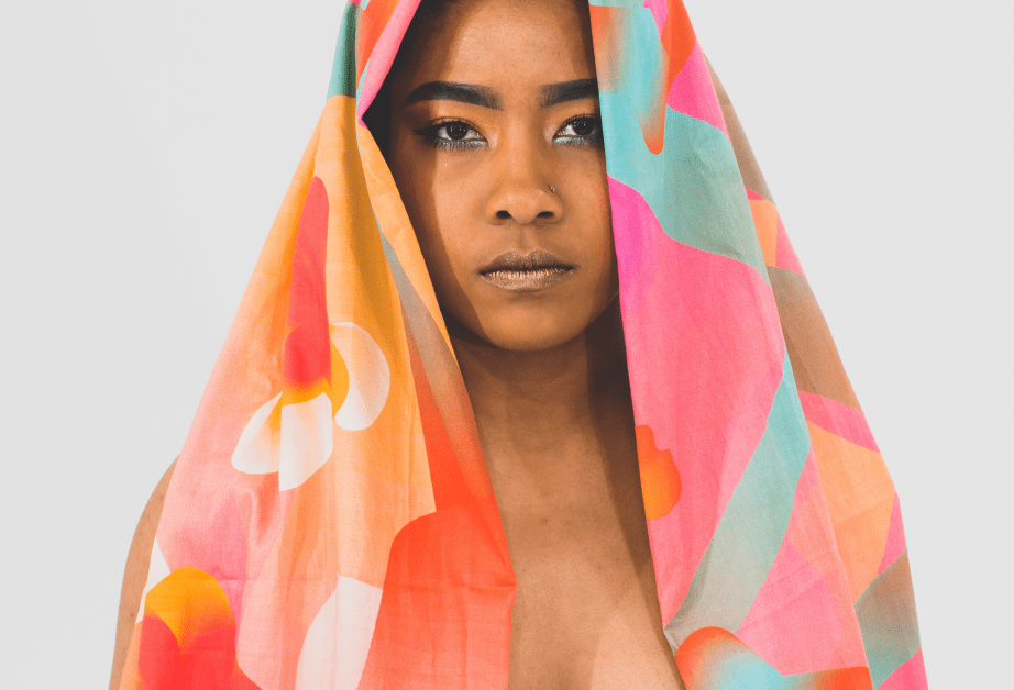 A photo of a woman wearing a colorful scarf over her head and body.
