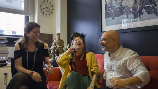 a photo of three people sitting on a couch and are having fun