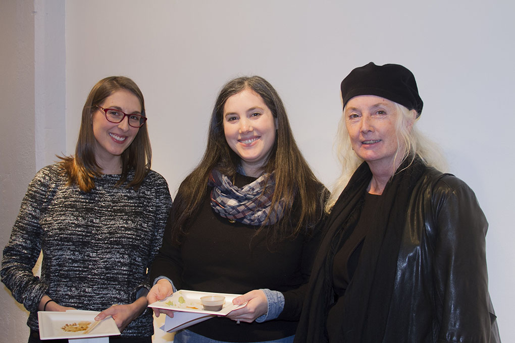 A photo of three women, some holding food plates.