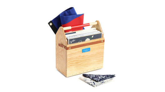 A wood toolbox that is holding some albums or books and a flag. Also near it there are some tissue napkins.