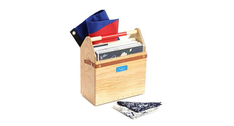 A wood toolbox that is holding some albums or books and a flag. Also near it there are some tissue napkins.