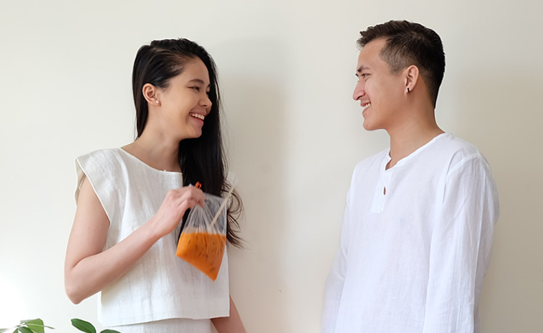 image of a man and a woman facing each other, and the woman has a plastic bag with orange organic material in it