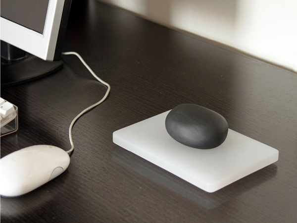 a black stone placed on a white piece of plastic is installed on a desk near a computer