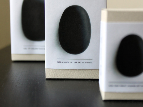 a close-up of black stones packed in cardboard boxes and on the label is a message saying: size: another year set in stone