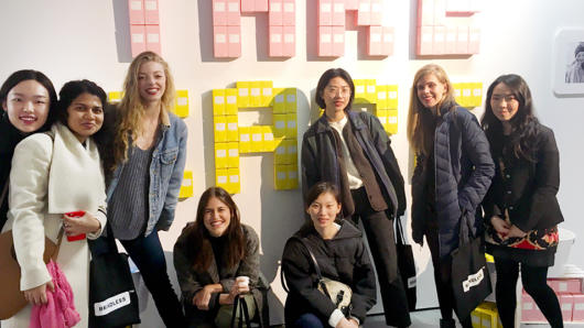 group photo of students in front of the Take Care sign on the wall