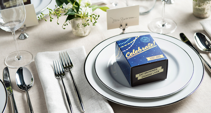 a box of cookies with the Celebrate title is placed on a white plate on the dinner table