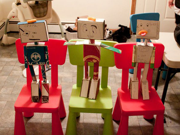 three cardboard-made characters on two red chairs and a green chair