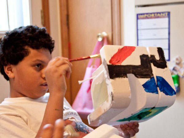 a child is painting with the brush on an object with rounded corners