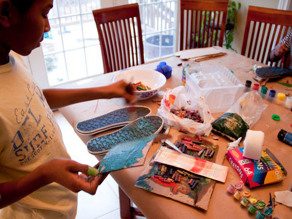 kids working with paint, brushes, and other materials at a table