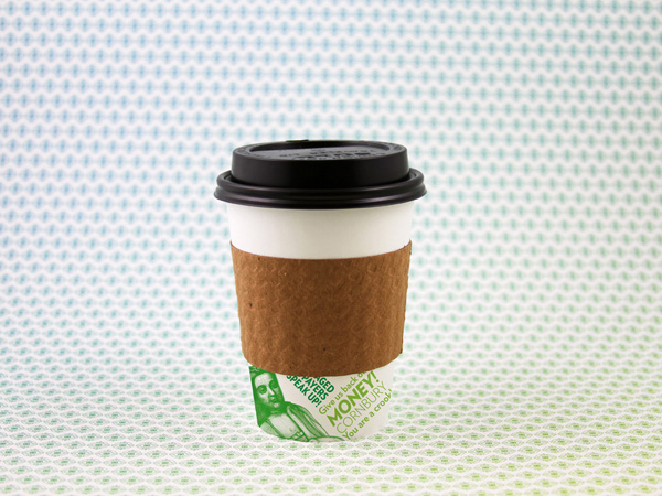 a to-go coffee cup with a green illustration at its bottom is photographed on a blue-green dotted background