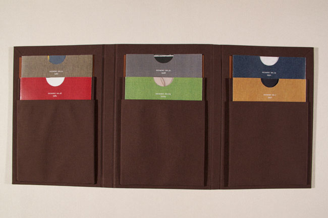 multicolor envelopes like blue, green, grey, orange, etc., inserted in a brown fabric holder