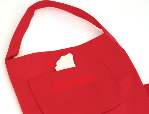 a red grocery back with the krasula logo n its front pocket
