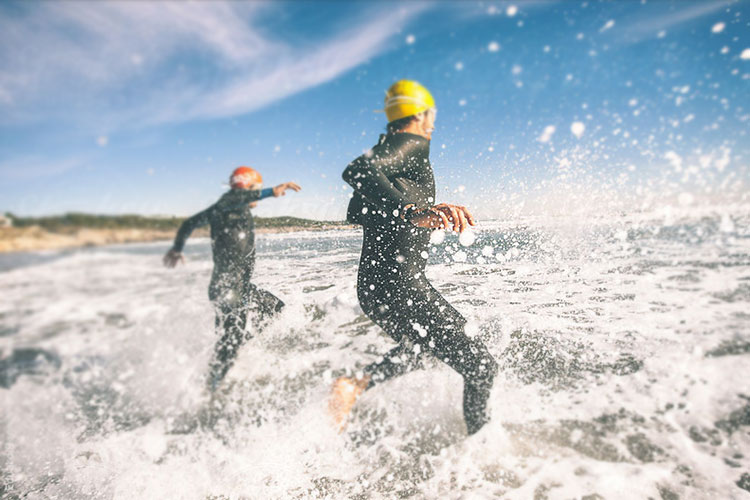 photo of two persons running into the ocean