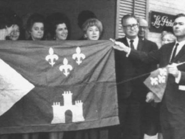a black and white group photo of people holding up a flag