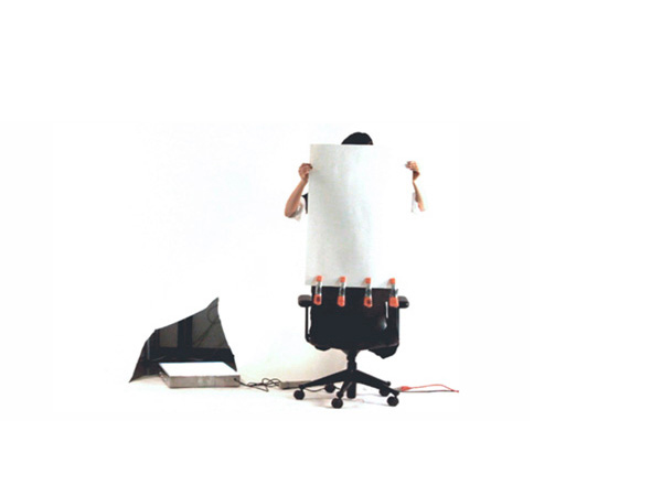 a person sitting on a chair is covering their face with a large piece of paper