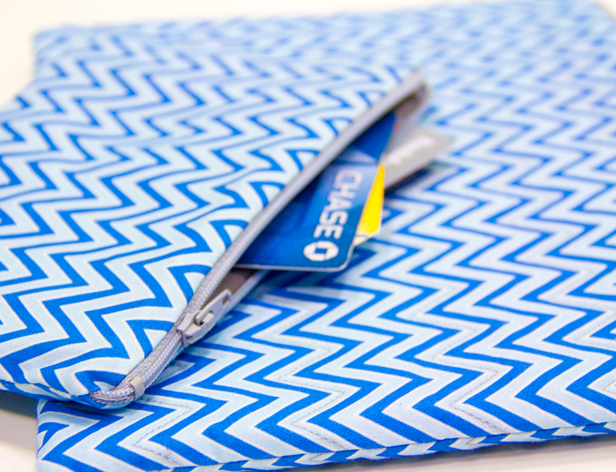 a small white and blue pocket with zipper and some cards in it