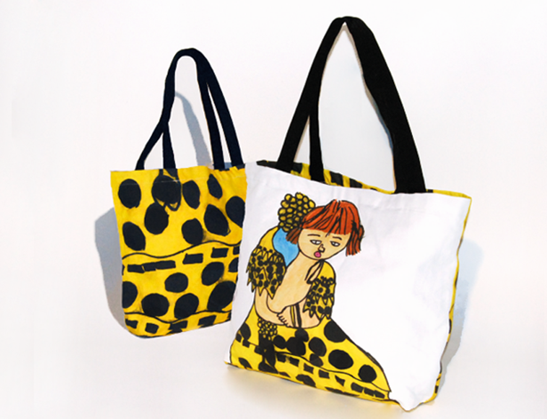 a fabric handbag with a yellow and black dots design and an illustration of a girl on one side of the bag