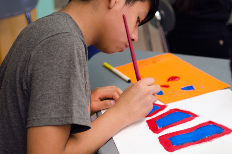 image of a boy painting with red and blue on a white paper