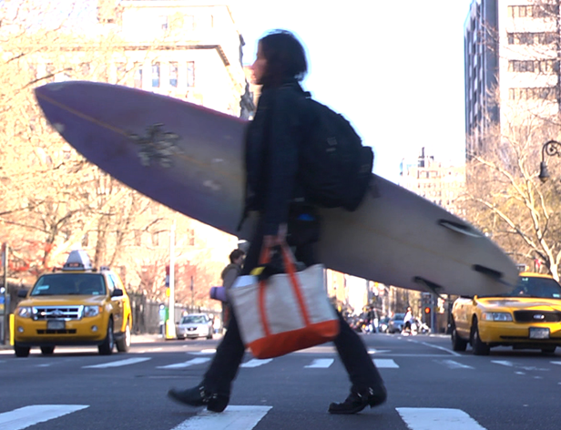 image of a person with a surfing board crossing a street