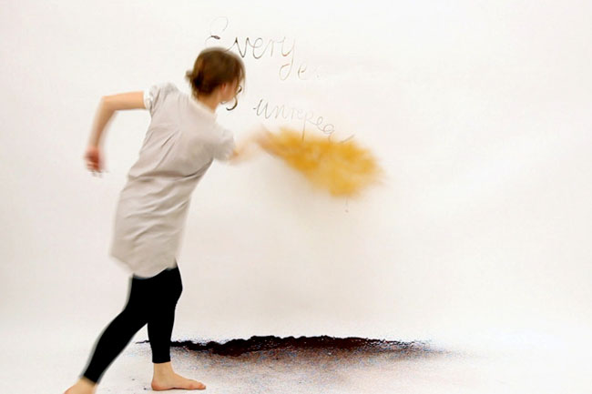 woman throwing orange powder at a white wall