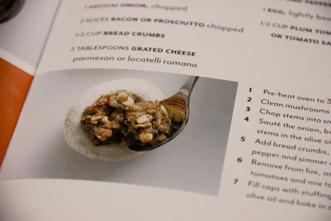 close-up photo of an image with a spoon pouring stuffing composition in a mushroom  from the cooking book