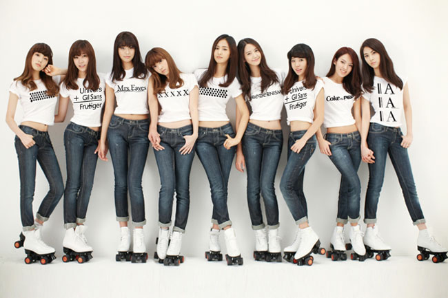 a group photo of nine girls with roller skaters, blue jeans, and white t-shirts with black text on them