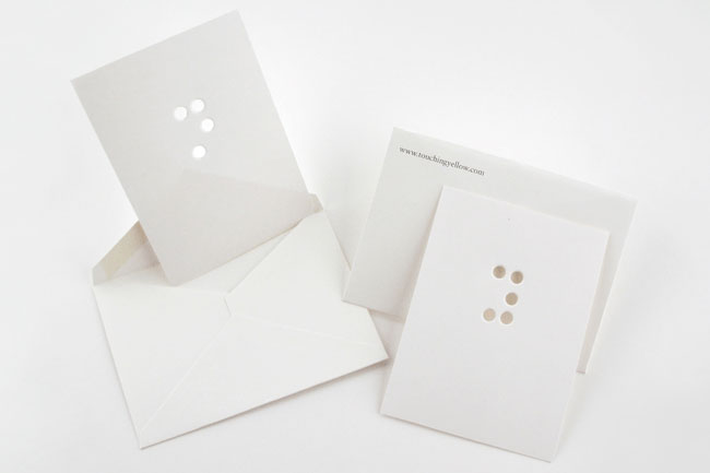 two envelopes, each with an invitation with braille writing on them made with holes