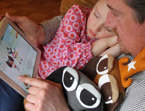 a man is reading a story from an iPad to his daughter