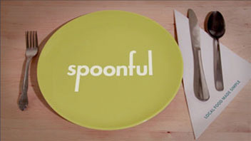 a green plate with a spoonful white logo on it, and fork, a steak knife, and a spoon besides