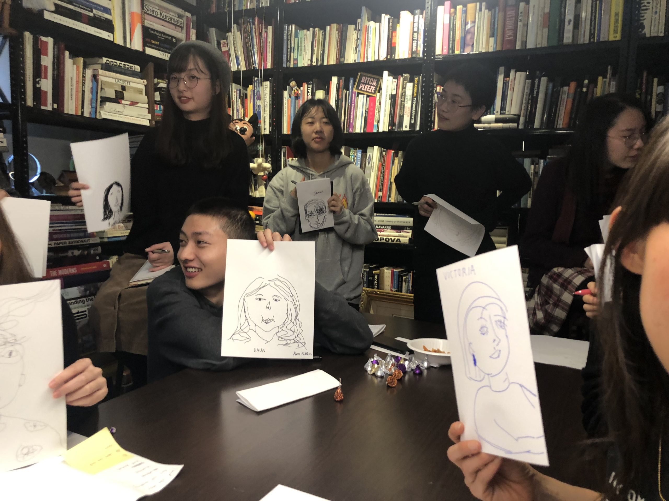 students holding up their drawings of portraits