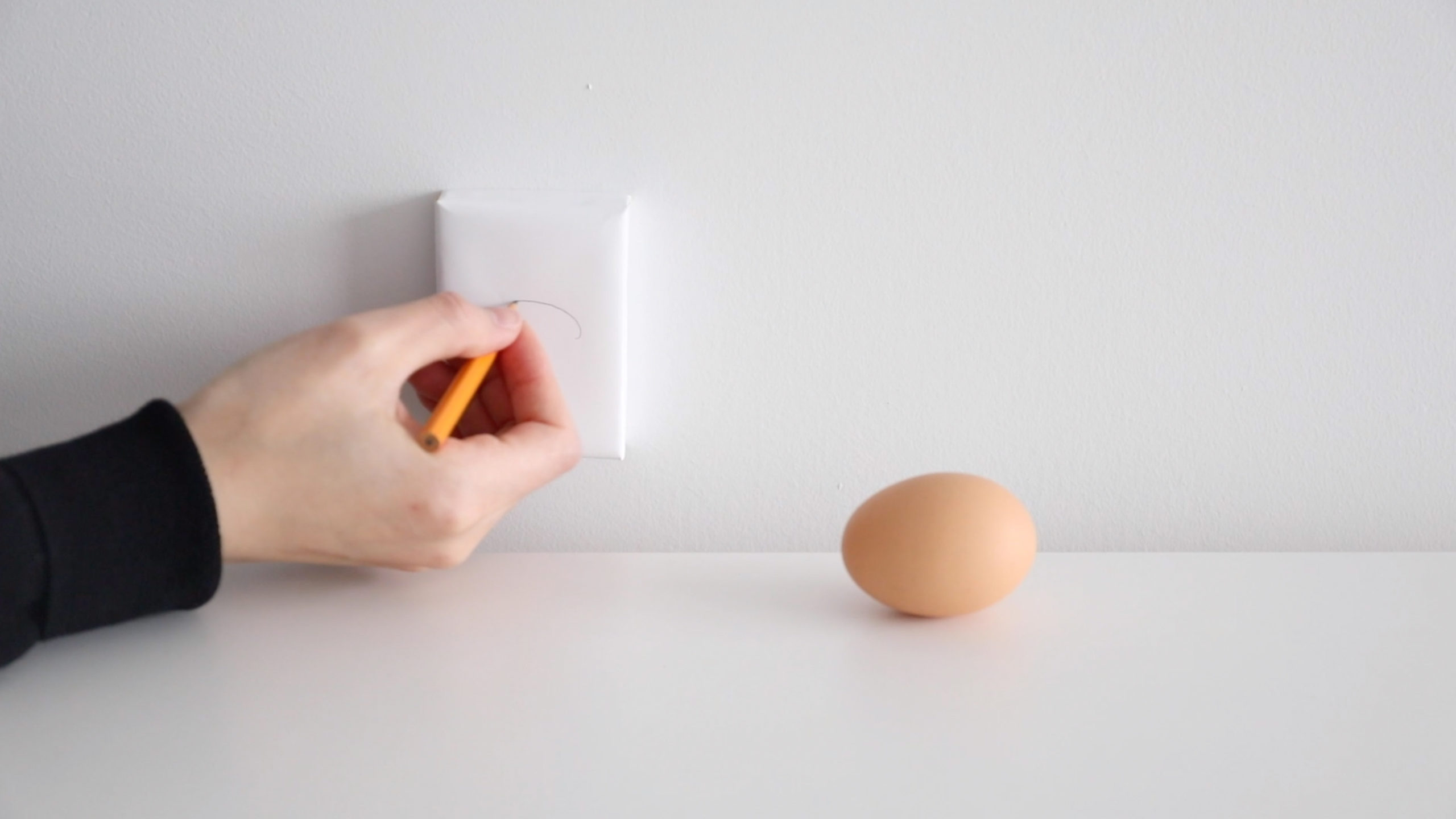 brown egg with hand drawing something on a paper