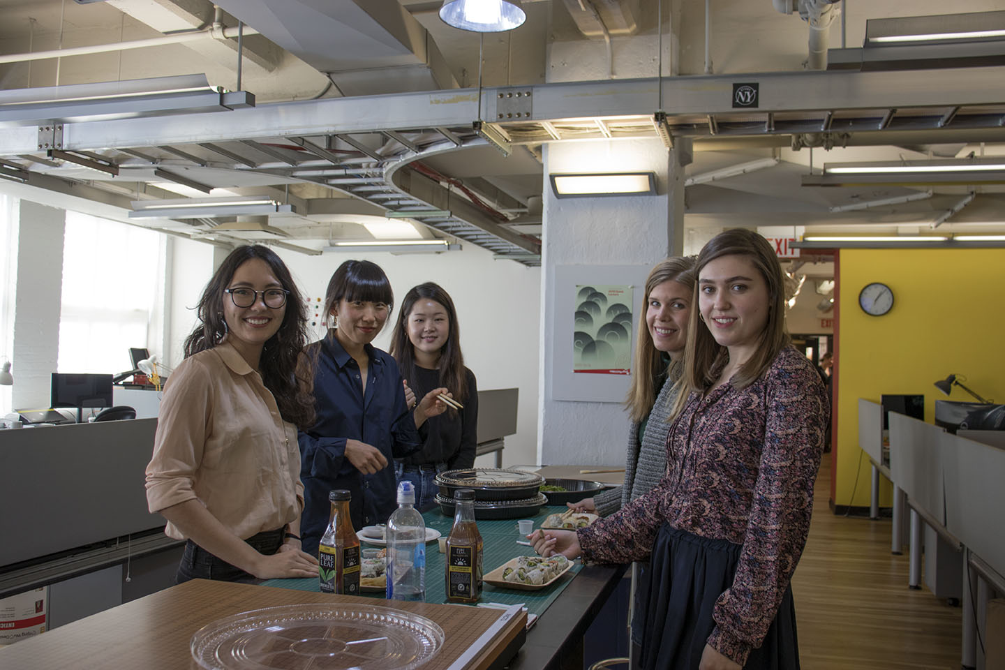 five students pose for a picture while eating sushi