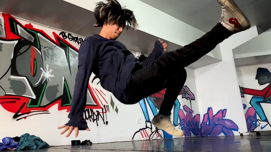 young person break dancing indoors with grafitti
