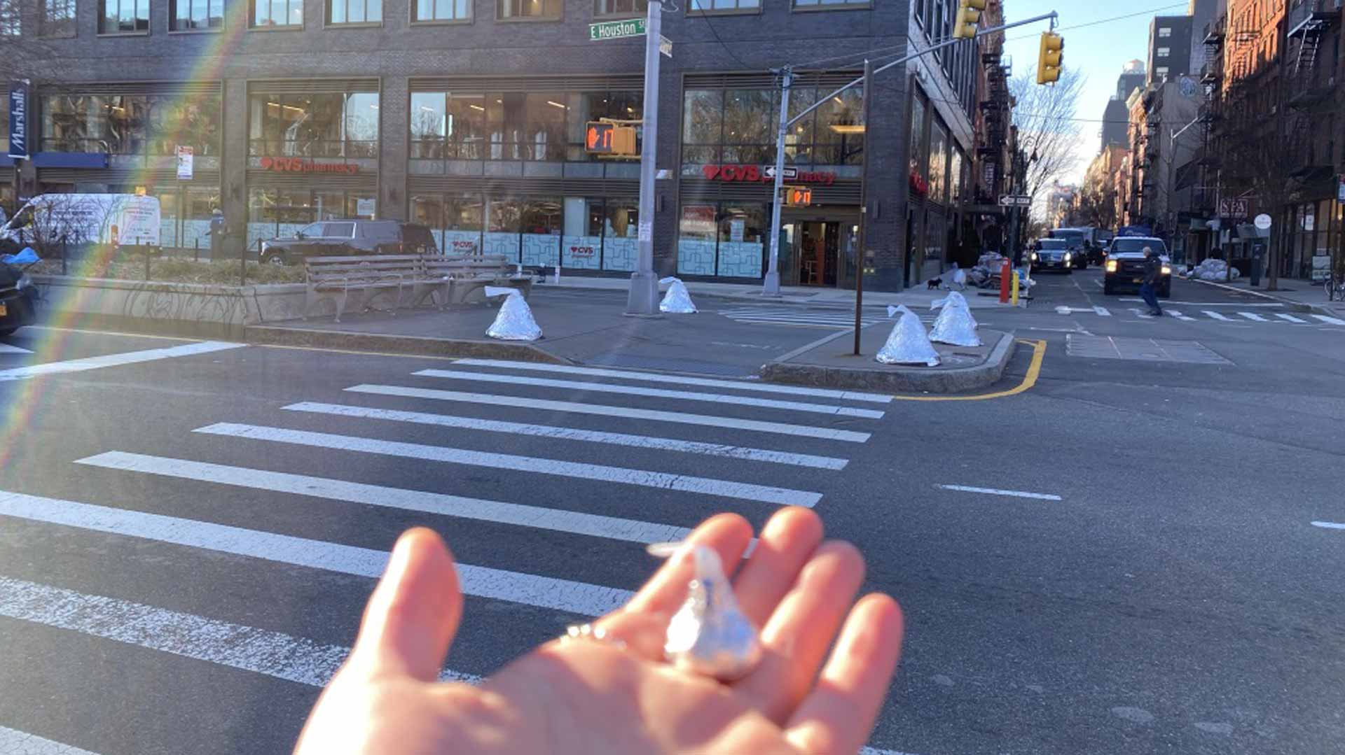 chocolate kiss in a person's hand in front of 4 giant hersey kiss scultures