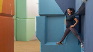 Samia Kallidis in tight workout clothes on a colorful geometric sculpture