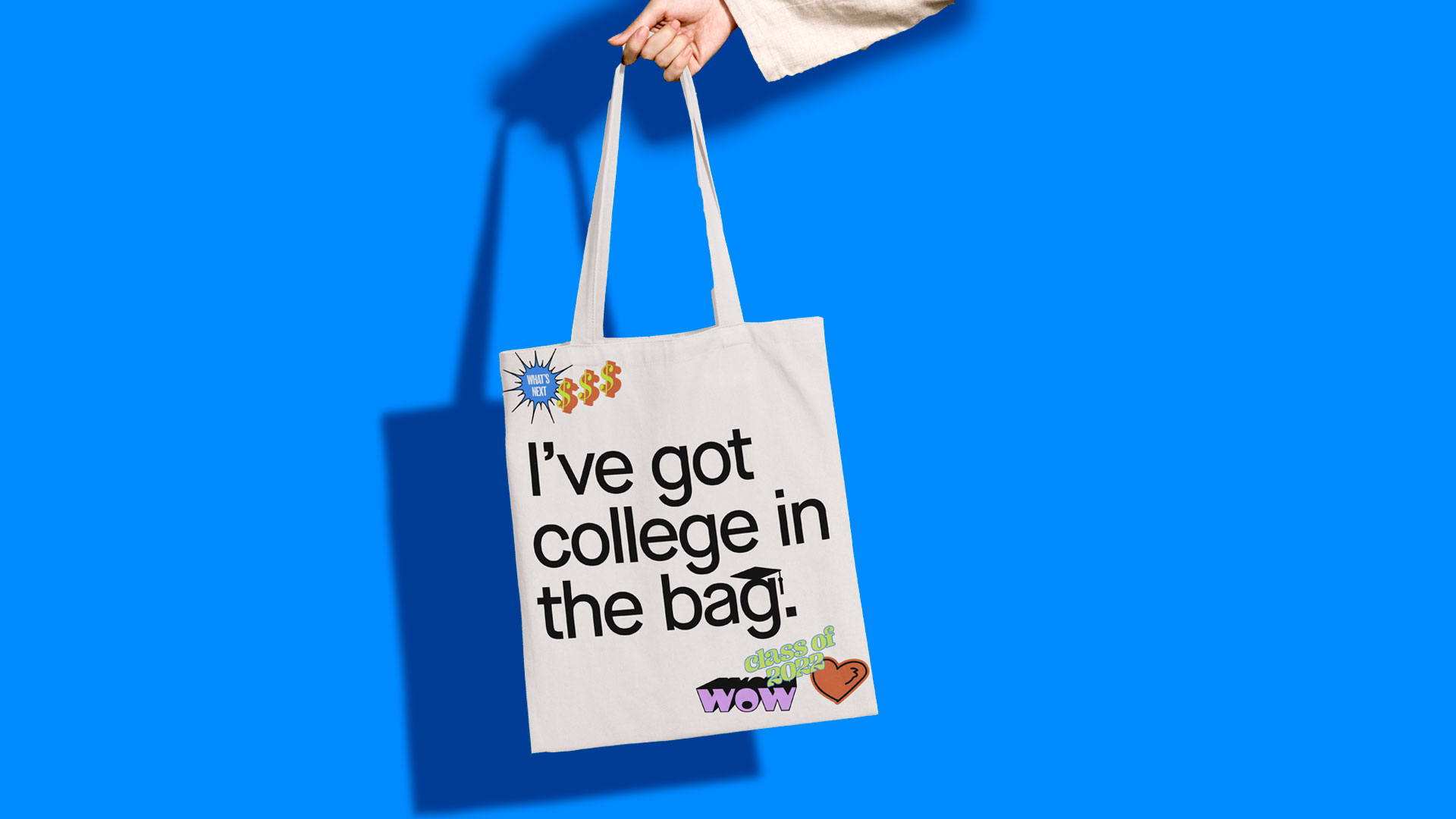 A hand holding a school me tote bag